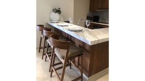 A modern kitchen with a marble countertop, wooden bar stools, and a built-in sink. - Sunset Suite (Cabo San Lucas)