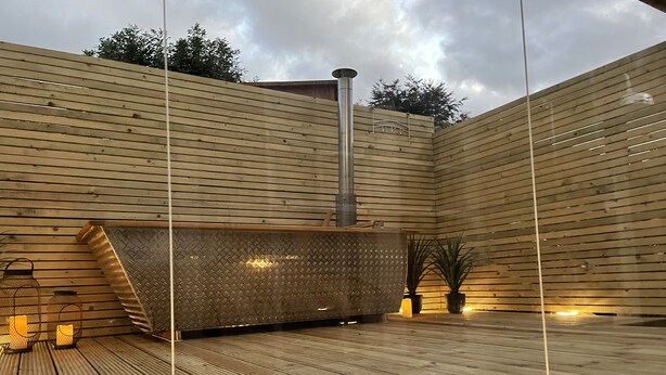A wooden deck with a built-in sauna, potted plants, and a metal sauna heater. - Luxury hotel style 2-bed home with hot tub central location (pet friendly) (Wooler)