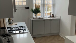 A modern kitchen with white cabinetry, a gas stove, a built-in oven, and a window with blinds. - Luxury hotel style 2-bed home with hot tub central location (pet friendly) (Wooler)