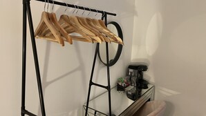 A room with a black metal rack holding wooden hangers, a glass coffee table with a black object on it, and a pink chair. - Luxury hotel style 2-bed home with hot tub central location (pet friendly) (Wooler)