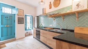 Une cuisine avec des armoires en bois, un plan de travail noir et un dosseret de carreaux disposés en motif chevron.
