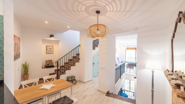 Un vaste espace de vie comprenant une table à manger en bois, un escalier et un luminaire suspendu.