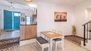 A dining area with a wooden table and chairs, a blue door, and a staircase. - Casa La Botica Frigiliana by Ruralidays (Málaga)