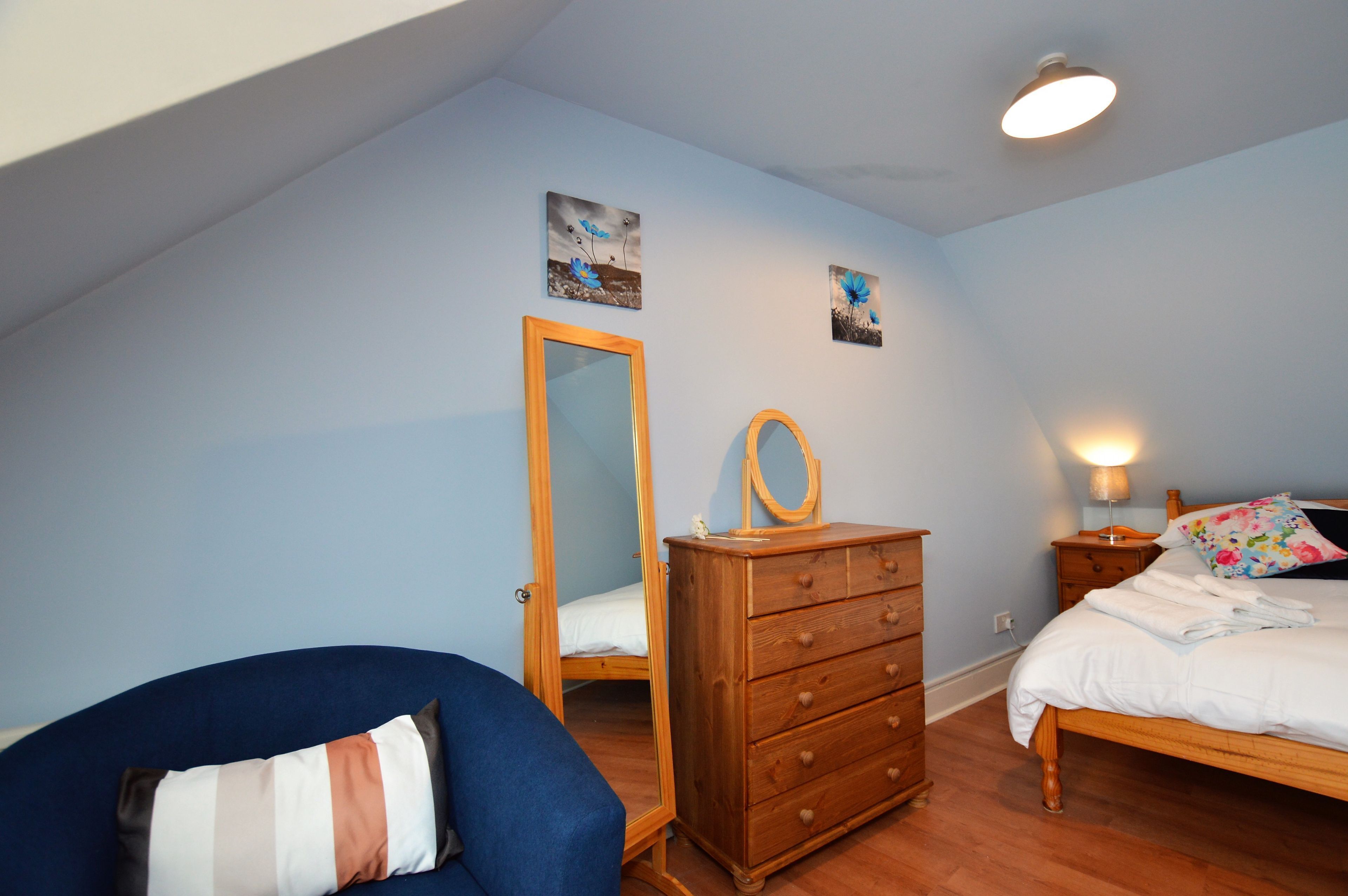 A bedroom with a bed, a dresser, a mirror, and a chair.