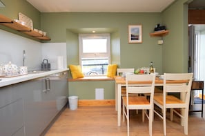 Une cuisine moderne avec un coin fenêtre, des meubles en bois et un espace repas avec des chaises blanches.