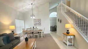 A spacious living room with a dining area, a staircase, and a view of the interior. - Wish Upon A Star 5 bed pool/jacuzzi spa heat included (Clermont)