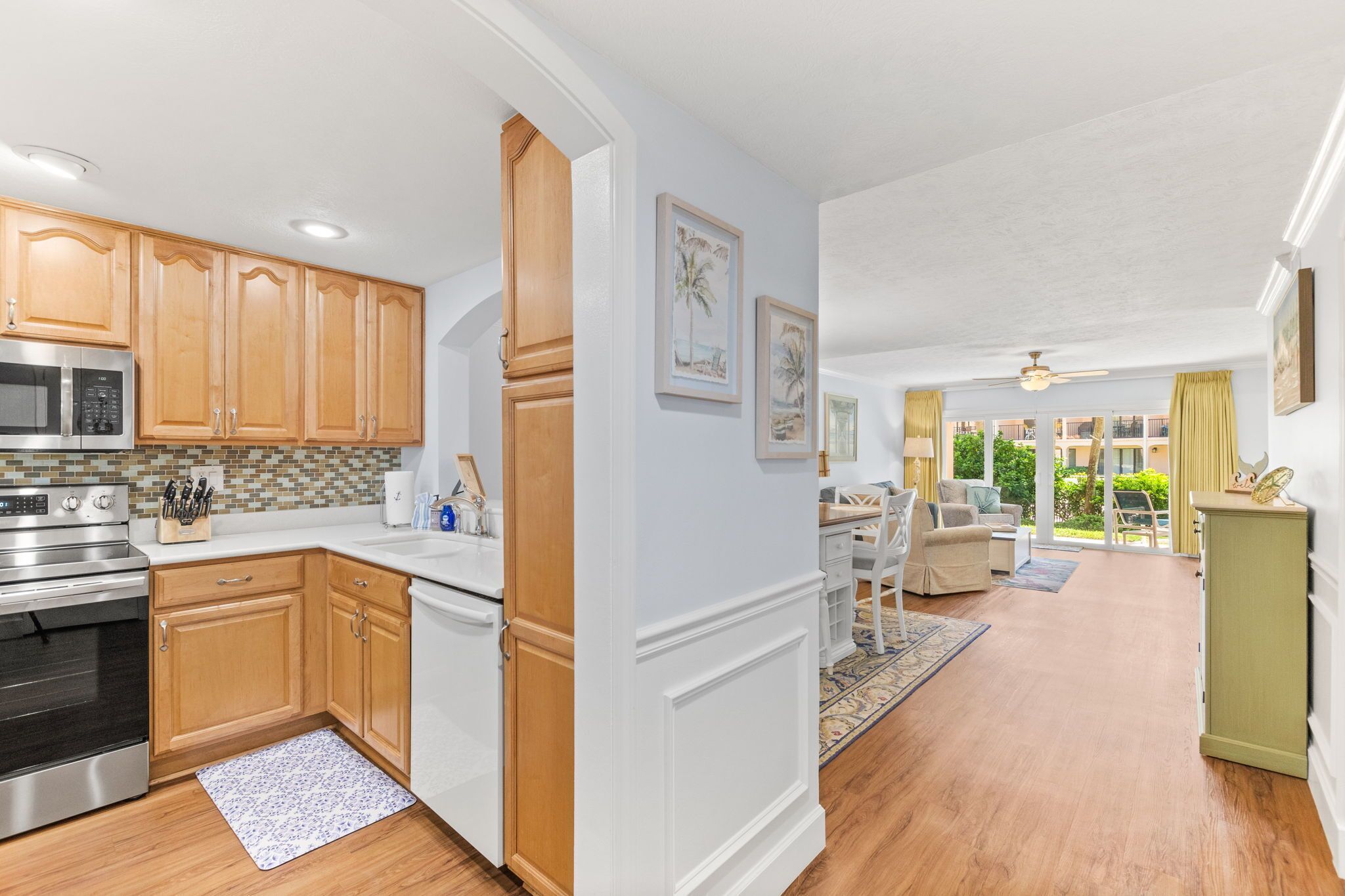 A modern kitchen with wooden cabinets, stainless steel appliances, and a dining area with a view.
