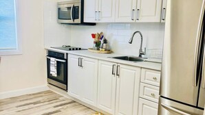 Una cocina moderna con armarios blancos, electrodomésticos de acero inoxidable y una alfombra amarilla estampada.