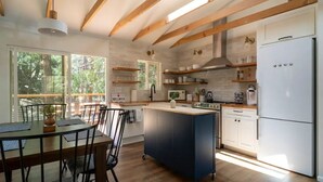 A modern kitchen with wooden beams, a central island, white cabinets, and a white refrigerator. - All New, 3 Bdrms, HOT TUB, near town and trails (Idyllwild-Pine Cove)