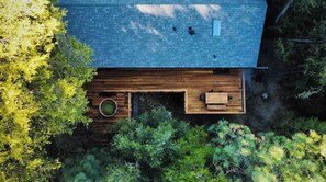 Vue aérienne d’une maison dotée d’une terrasse en bois, entourée d’une végétation luxuriante.