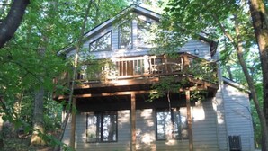 A two-story wooden house with a deck, surrounded by trees. - Relaxing Wintergreen Chalet (Wintergreen Resort)