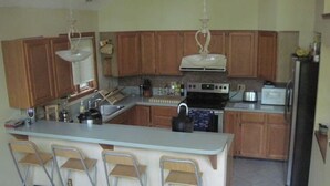 A kitchen with wooden cabinets, a central island with bar stools, stainless steel appliances, and a refrigerator. - Relaxing Wintergreen Chalet (Wintergreen Resort)
