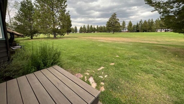 A wooden deck leading to a grassy yard with trees and a cloudy sky. - Golf Course, Close to YNP, Groceries, Restaurants (Island Park)