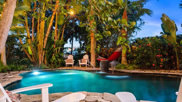 A pool with white lounge chairs and a red hammock. - Funky coconut luxury apartment (Dunedin)
