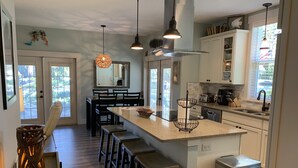 A modern kitchen with a central island, bar stools, pendant lighting, and a large window. - Funky coconut luxury apartment (Dunedin)