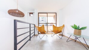 A modern interior with a glass table, two chairs, a hanging light fixture, and a view through a glass door. - Hotel Medallo City (Medellín)