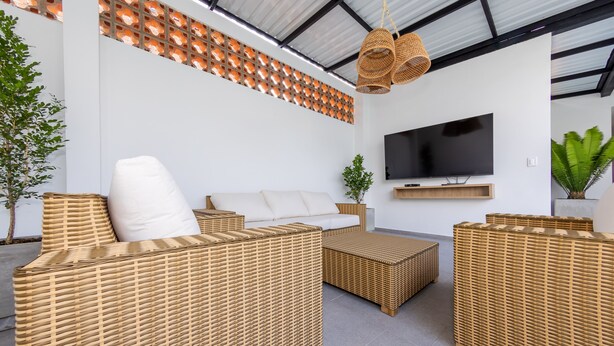 A modern living room with wicker furniture, a flat-screen TV, and a ceiling with a grid-like pattern. - Hotel Medallo City (Medellín)