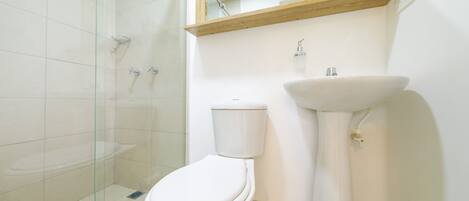 A bathroom with a toilet, sink, and glass shower enclosure.