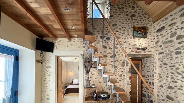 Un intérieur rustique avec un mur en pierre, un escalier en bois et une porte bleue.