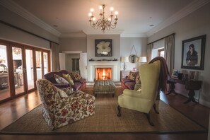 A spacious living room with a fireplace, comfortable seating, and a chandelier.