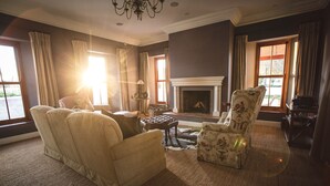 A cozy living room with a fireplace, a sofa, a floral armchair, and a coffee table.