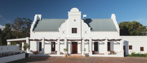A white building with a symmetrical facade, a central entrance, and a covered porch area.