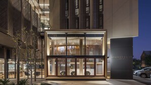 A modern building with a glass facade, a sign reading "STOREHOUSE," and a well-lit entrance area with plants and seating. - Vibe Hotel Adelaide (Adelaide)