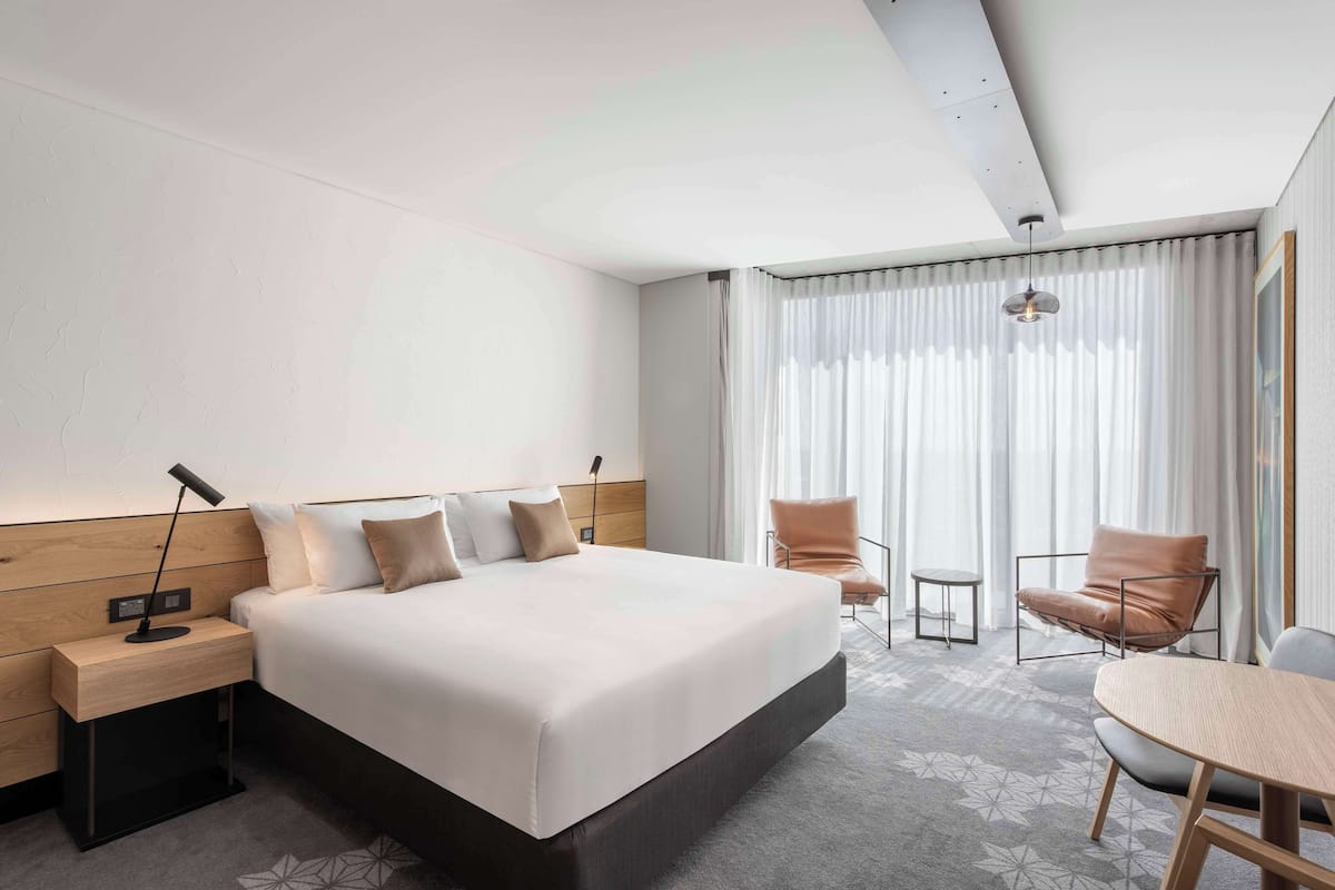 Una habitación de hotel moderna con una cama grande, un escritorio, una silla y una mesita.