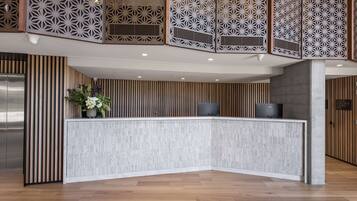 A reception desk with a modern design, flanked by wooden paneling and a decorative screen.