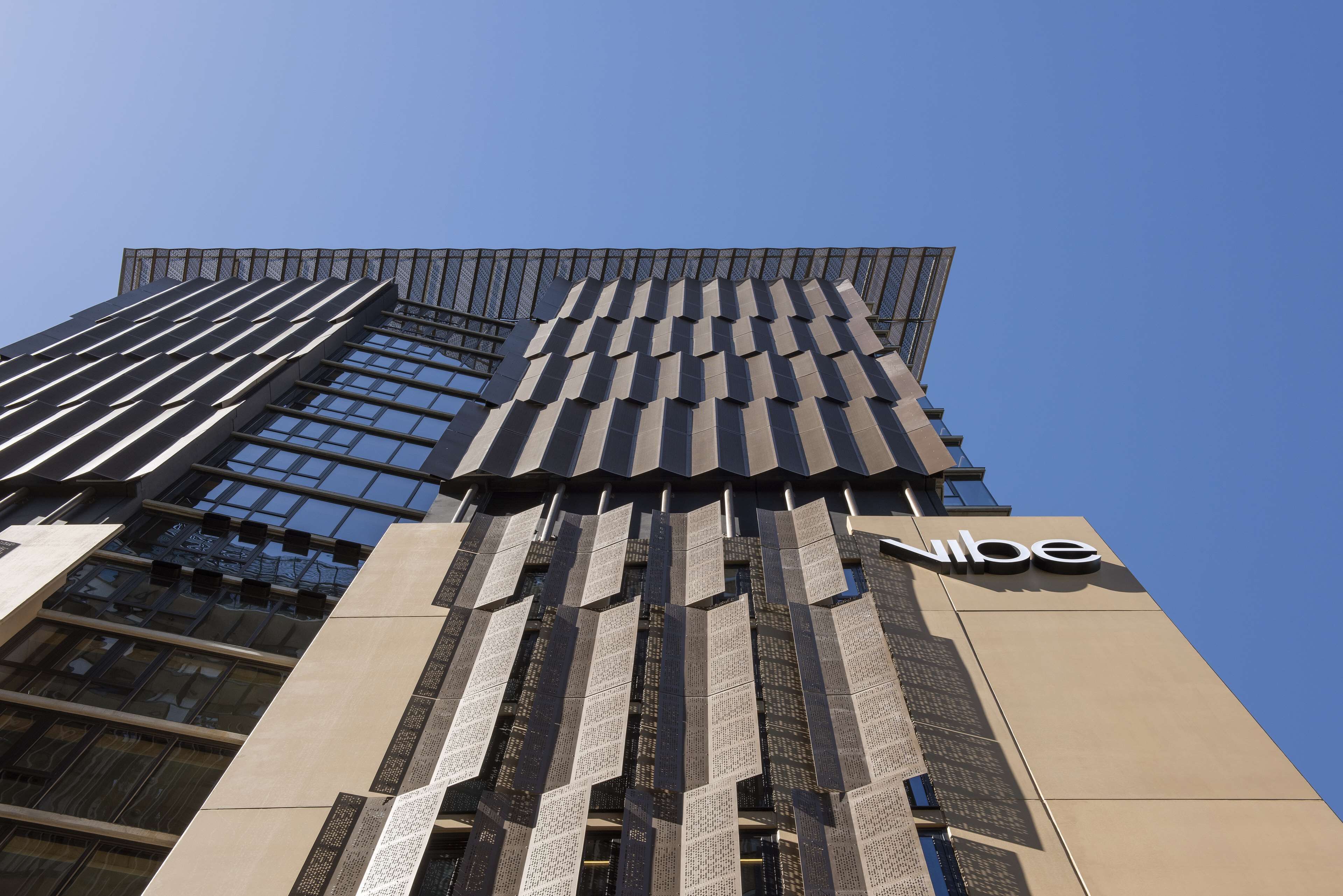 A modern building with a prominent 'vibe' sign, featuring a unique facade with vertical slats and large windows.