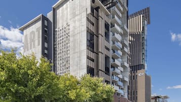 Un hotel moderno de varios pisos con un llamativo letrero 'ART', amplias ventanas y un estacionamiento con coches.