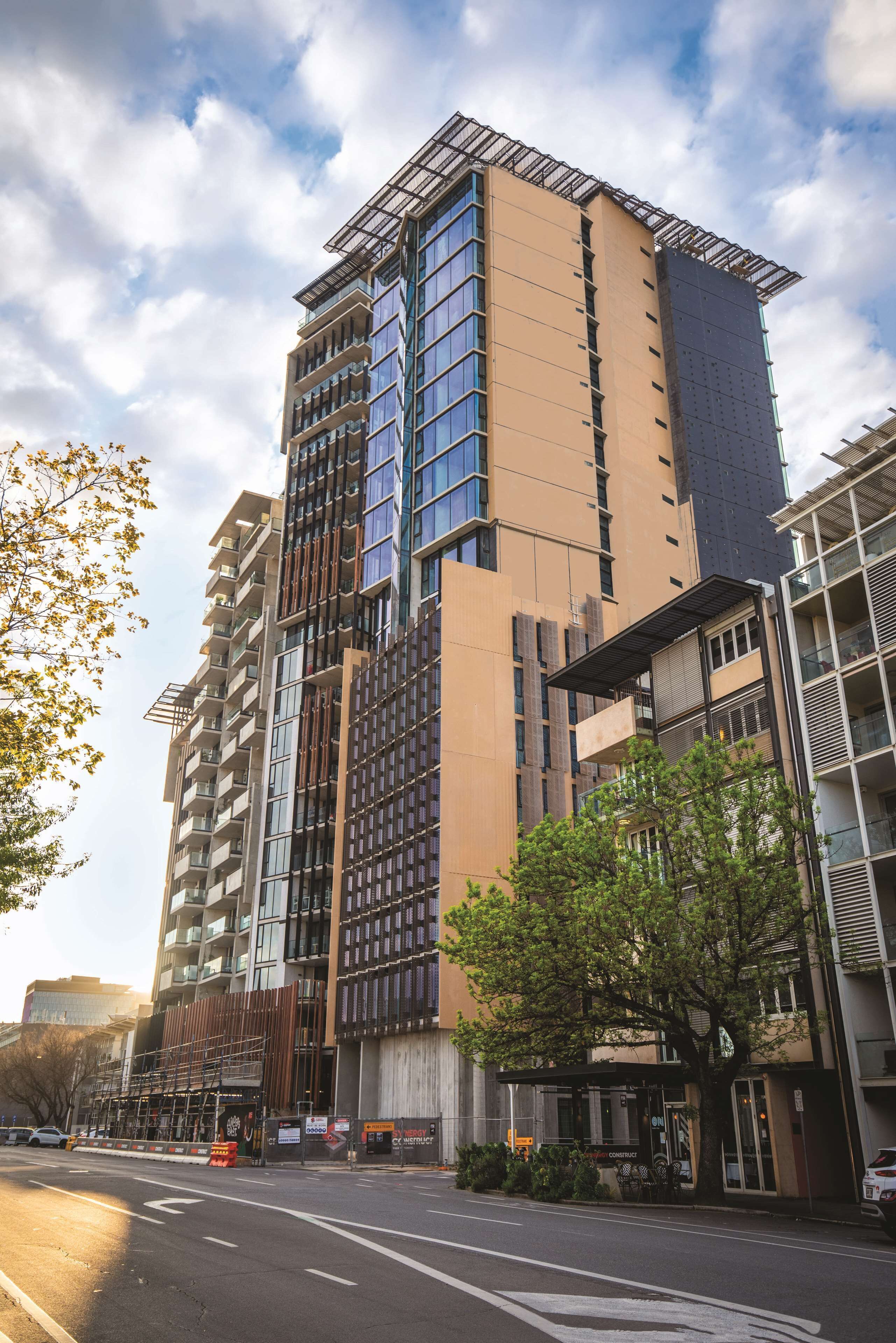 Een modern hoog gebouw met meerdere verdiepingen, grote ramen en een gevel van glas en beton.
