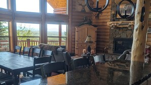 A spacious kitchen with a large island, wooden cabinetry, and a stone fireplace.