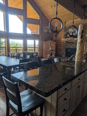 A spacious kitchen with a large island, wooden cabinetry, and a stone fireplace.