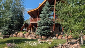 A lodge with a wooden exterior, a stone foundation, and a stone pathway leading to the entrance.