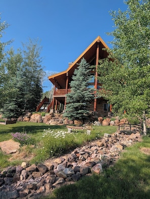 A lodge with a wooden exterior, a stone foundation, and a stone pathway leading to the entrance.