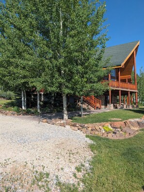 Un lodge con facciata in pietra, veranda in legno e un grande albero di fronte.