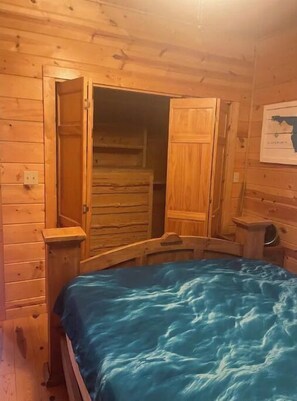 Cozy cabin room with a bed, wooden wardrobe, and a map on the wall.