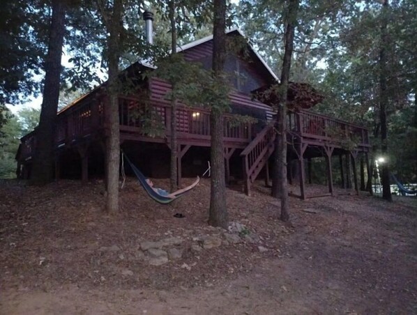 Escape to a secluded cabin surrounded by a wooded forest, where a hammock beckons on a covered porch.