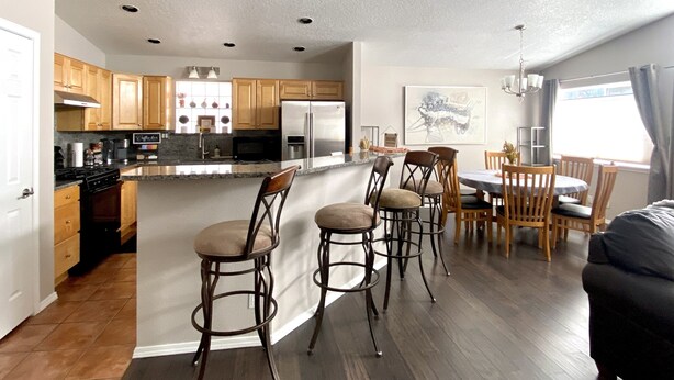 A modern kitchen with wooden cabinets, a stainless steel refrigerator, and a central island with bar stools. - Prime Northeast Heights Location - 3 Bedroom - 2.3 mi to Balloon Fiesta Park! (Albuquerque)