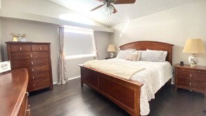 A bedroom with a wooden bed, a ceiling fan, a nightstand with a lamp, and a dresser. - Prime Northeast Heights Location - 3 Bedroom - 2.3 mi to Balloon Fiesta Park! (Albuquerque)