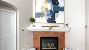 A living room with a fireplace, a framed abstract painting above it, and two baskets on either side. - Prime Northeast Heights Location - 3 Bedroom - 2.3 mi to Balloon Fiesta Park! (Albuquerque)