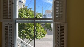 A window with white shutters, a clear view of a street with a tree and a white fence. - 1-bedroom in the Borough, just steps to the water (Stonington)