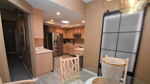 A compact kitchen with modern appliances, a dining area with a glass table, and a view of the adjacent living space. - 224 Calle Florista, Laguna De LaPaz (La Quinta)