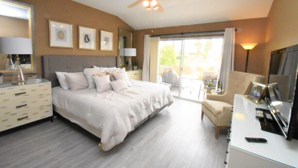 A hotel room with a large bed, a desk with a lamp, a chair, and a balcony with a view. - 224 Calle Florista, Laguna De LaPaz (La Quinta)