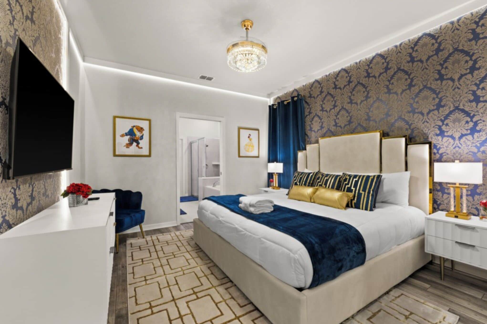 A hotel room with a bed, bedside tables, a TV, a desk, a chair, and a door.
