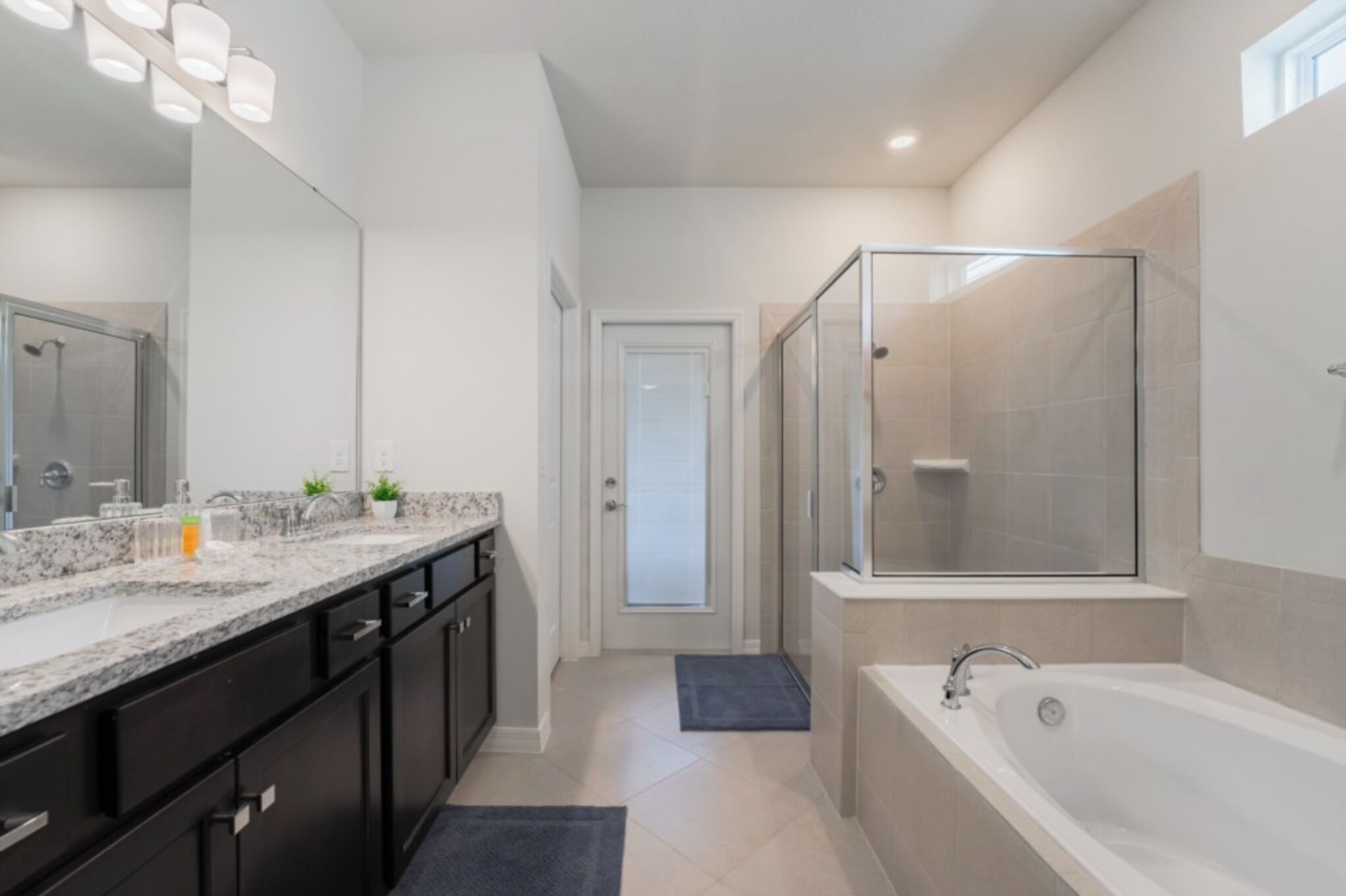 Une salle de bain moderne avec un grand miroir, une douche, une baignoire et un meuble-lavabo.