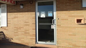 A brick building with a glass door, a sign that reads "OFFICE", and a "NO SMOKING" sign. - Hotel Prairie Winds Carthage Keokuk Hwy 136 (Carthage)