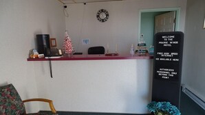 A reception desk with a clock, a small Christmas tree, and a welcome sign. - Hotel Prairie Winds Carthage Keokuk Hwy 136 (Carthage)