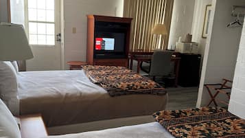 Habitación de hotel con dos camas, un televisor, un escritorio con computadora y una ventana.